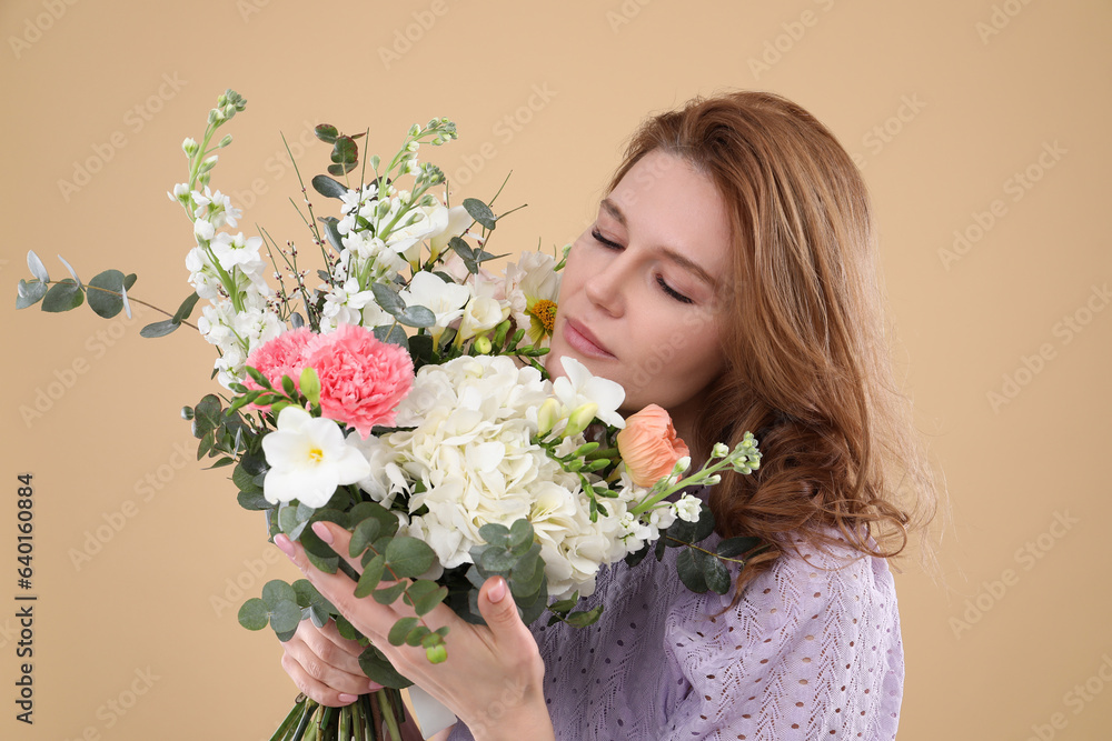 Poster Beautiful woman with bouquet of flowers on beige background