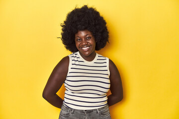 Fototapeta na wymiar African-American woman with afro, studio yellow background happy, smiling and cheerful.