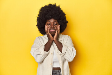 Fototapeta na wymiar African-American woman with afro, studio yellow background whining and crying disconsolately.