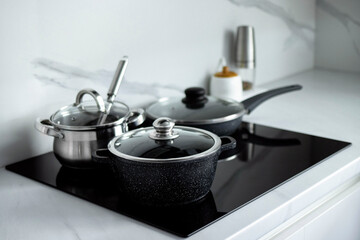 Fototapeta na wymiar The saucepans stand on an electric induction stove. Modern modernized kitchen in the style of minimalism. Kitchen interior