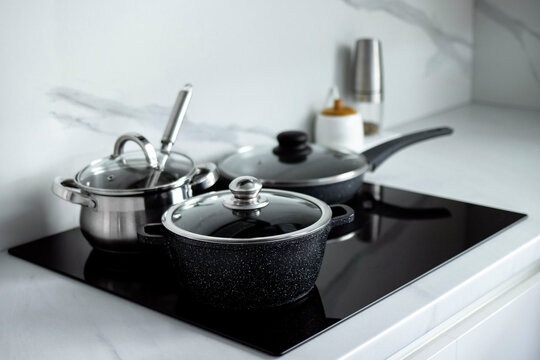 The saucepans stand on an electric induction stove. Modern modernized kitchen in the style of minimalism. Kitchen interior