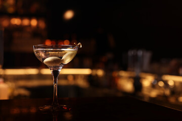 Martini glass with fresh cocktail and olives on bar counter, space for text