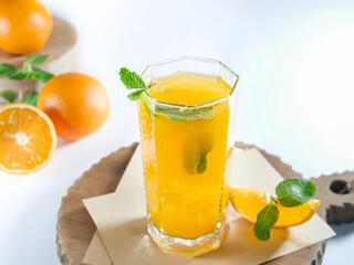 close up view of a glass of refreshing orange juice with ice and mint for summer drink, isolated on white, copy space