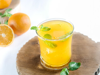 close up view of a glass of refreshing orange juice with ice and mint for summer drink, isolated on white, copy space