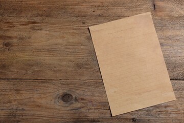 Sheet of old parchment paper on wooden table, top view. Space for text