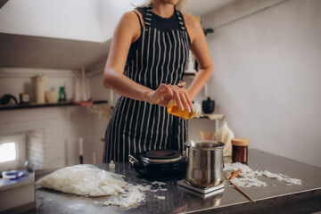 Woman making aromatic candles at white table indoors, closeup