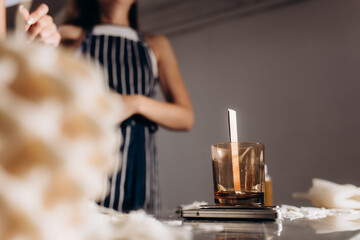 Handmade soy wax candle workshop. Young girl pouring liquid wax into the mold