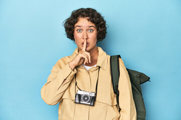 Young traveler woman with vintage camera keeping a secret or asking for silence.