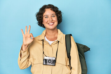 Young traveler woman with vintage camera cheerful and confident showing ok gesture.