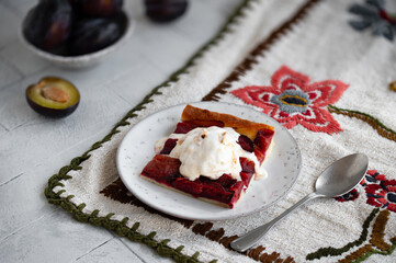 Piece of Fresh baked German Plum cake Zwetschgenkuchen with a scoop of ice cream in a rustic style. Healthy autumn food.