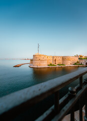 Taranto's Aragonese Castle by day with railing in the foreground