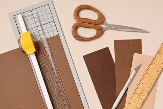 Top view over paper cut tools, scissors, cutter, cutting mat, and crafted paper objects. DIY trendy project concept. Flat lay