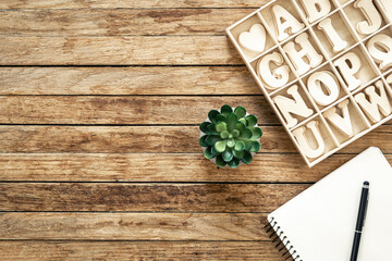 Set of wooden letters of the English alphabet and a notepad on a wooden background, top view.