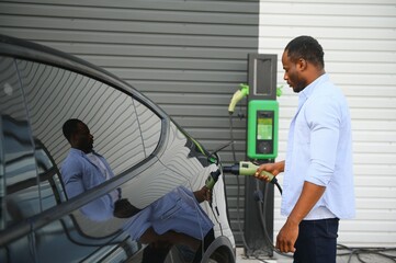 African American man charging his electric car.