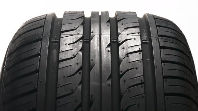 Rotation of a New Tire. New car wheel close-up slowly spinning showing tread pattern on white background