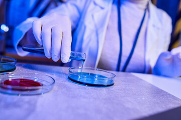 cropped view of scientist pouring liquid in petri dish, exploring extraterrestrial life