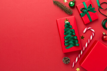Gift boxes with paper's rools and christmas decoration on color background, top view