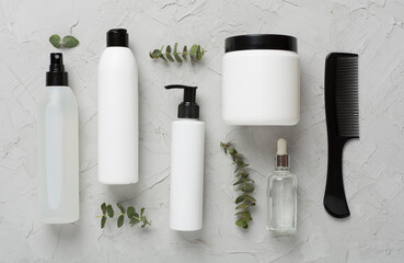 Professional hair care products with comb on concrete background, top view