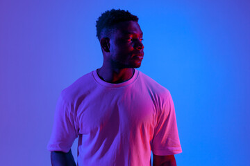 serious african american man looking away in neon lighting, portrait of guy in red blue lighting