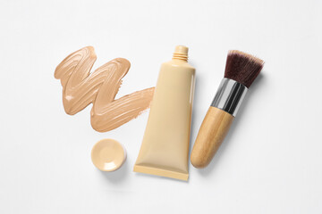 Liquid foundation, makeup brush and swatch on white background, flat lay