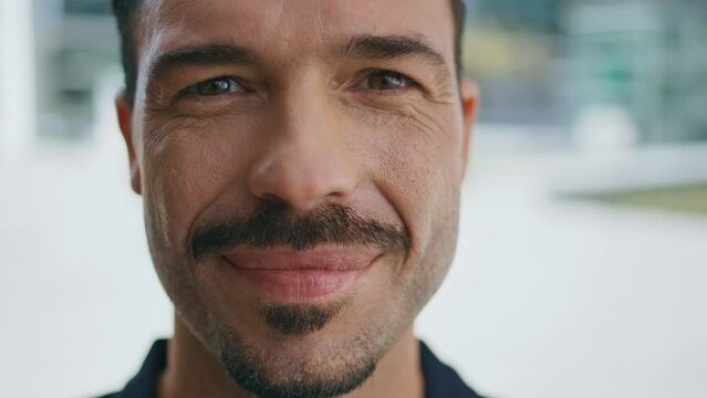 Closeup hispanic man face smiling camera at sunny city. Portrait businessman 