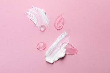 Samples of cosmetic gel and cream on pink background, top view