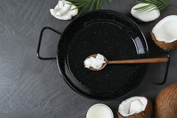 Flat lay composition with frying pan and organic coconut cooking oil on grey table, space for text
