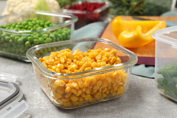 Containers with corn and fresh products on light gray table. Food storage