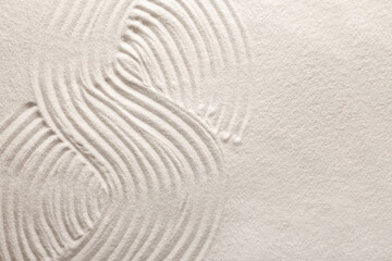 Fototapeta na wymiar Pattern drawn on white sand, top view with space for text. Zen garden