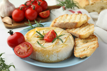 Fototapeta na wymiar Tasty baked brie cheese with rosemary, cherry tomatoes and bread on white table, closeup