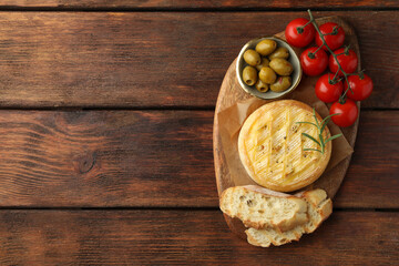 Tasty baked brie cheese served on wooden table, top view. Space for text