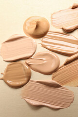 Samples of skin foundation on beige background, closeup