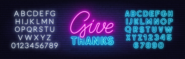 Give Thanks neon sign on brick wall background.