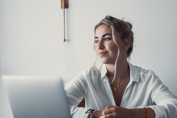 Thoughtful millennial student girl sitting at table with laptop, open books, looking away, thinking over training course, learning webinar, online lesson, test. Elearning, distance work from home. - Powered by Adobe