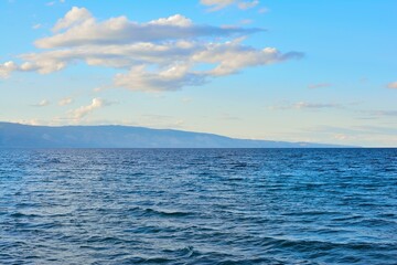 Obraz premium Beautiful lake waves with cloudy blue sky and mountains background