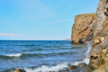 Scenic lake coast landscape rock waves. Blue sky and clear water.
