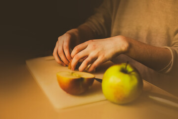 A woman is seen preparing slices of apples on a wooden cutting board for a homemade charlotte. The domestic cooking and importance of home-cooked meals and family traditions.