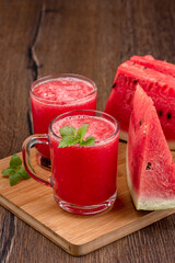 Close-up glass mug and glass with watermelon juice, mint leaves and watermelon pieces.