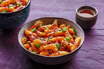 Tteokbokki or topokki and rabokki, Korean street food, spicy rice cakes in red pepper gochujang sauce, a popular dish, with a drink