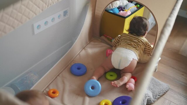 baby crawling first steps. baby toddler gets out of the playpen crib learns to crawl plays. happy family kid dream concept. baby toddler play in crib playpen indoors in kindergarten lifestyle