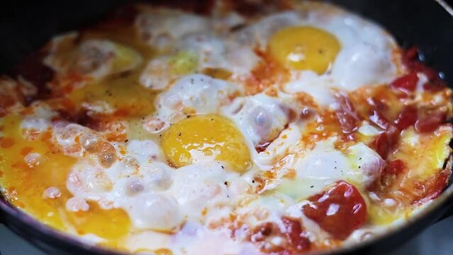 Fry eggs and vegetables in a frying pan close-up. Shakshuka cooking. Healthy fresh vegetables. Cooking. Vegetarian food. Assorted vegetables. Cooking.