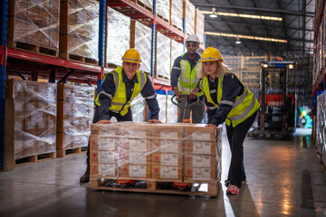 Warehouse workers working factory cargo hand pulling pallet truck, stack cardboard boxes on wooden...