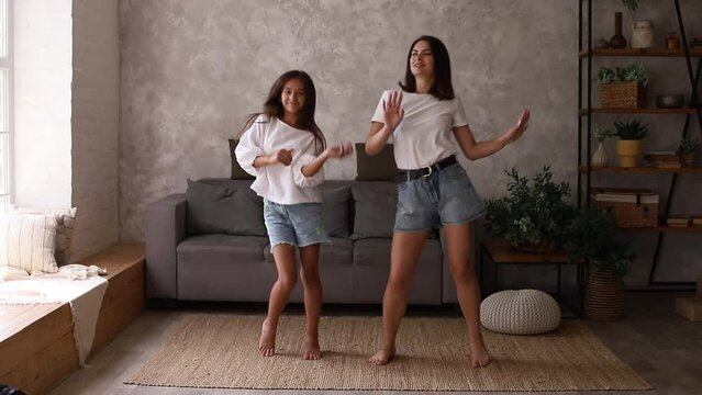 Mother and daughter teenager having fun dancing in living room. Parenting concept.