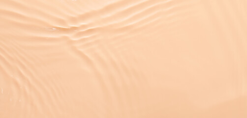 Water beige surface abstract background. Waves and ripples texture of cosmetic aqua moisturizer with bubbles.
