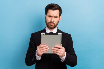 Photo of doubtful unsure assistant dressed black suit reading news modern gadget isolated blue...
