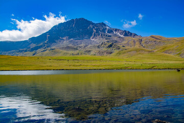 Small lake on top of a mountain. Crystal clear lake and mountain. Beautiful landscape with lake, fields and mountain