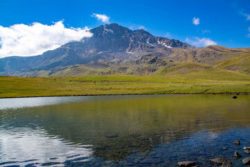 Small lake on top of a mountain. Crystal clear lake and mountain. Beautiful landscape with lake, fields and mountain