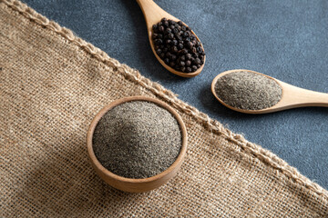 Ground black pepper with grains of black pepper on dark background