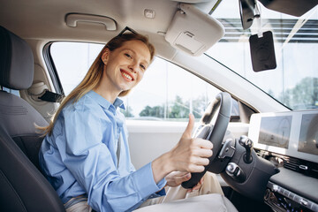 Woman smiling and holding steering wheel in her electric car