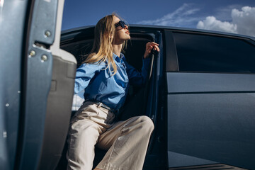 Woman sitting inside her electric car with open door